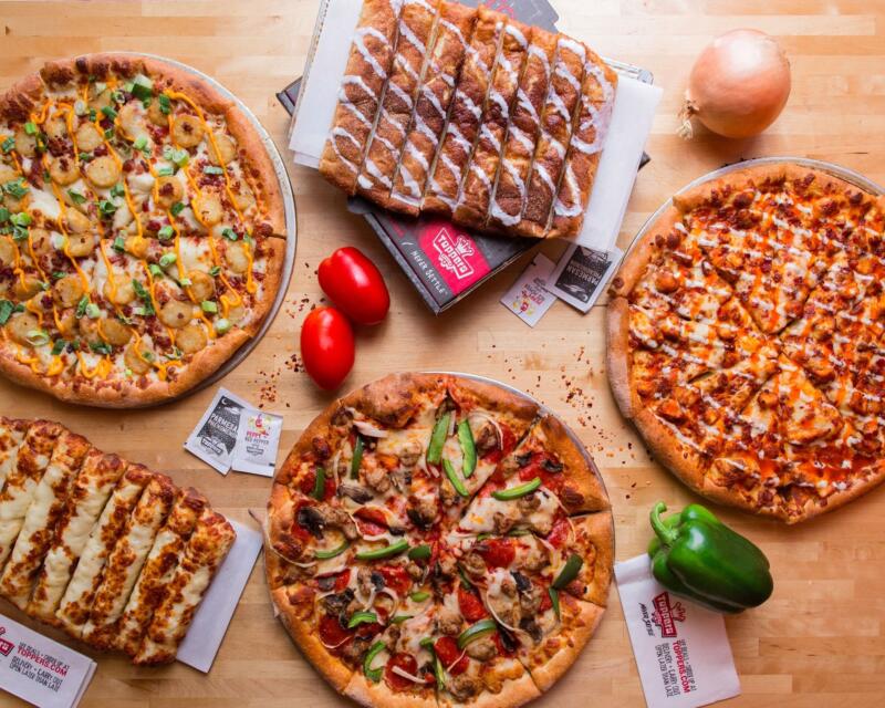 Toppers Pizza for website Pizza and breadsticks on a table in an ad from Topper's Pizza