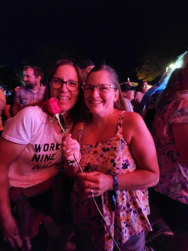 2 girls holding a rose at a concert
