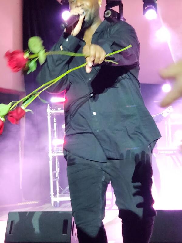 Man on stage with several roses handing them out