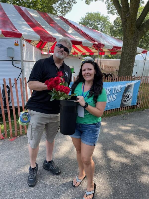 Man and woman holding a bucket of roses at a festival
