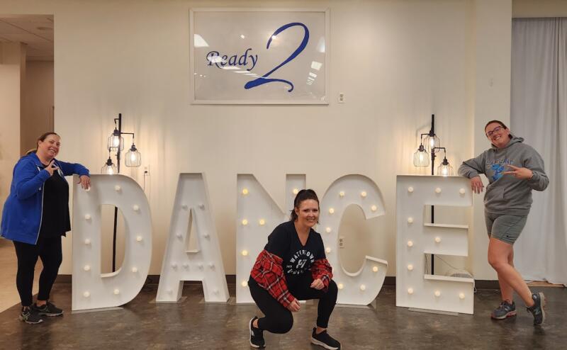 3 women posing in front of sign that says "DANCE" at Ready 2 Dance in Watertown Wi