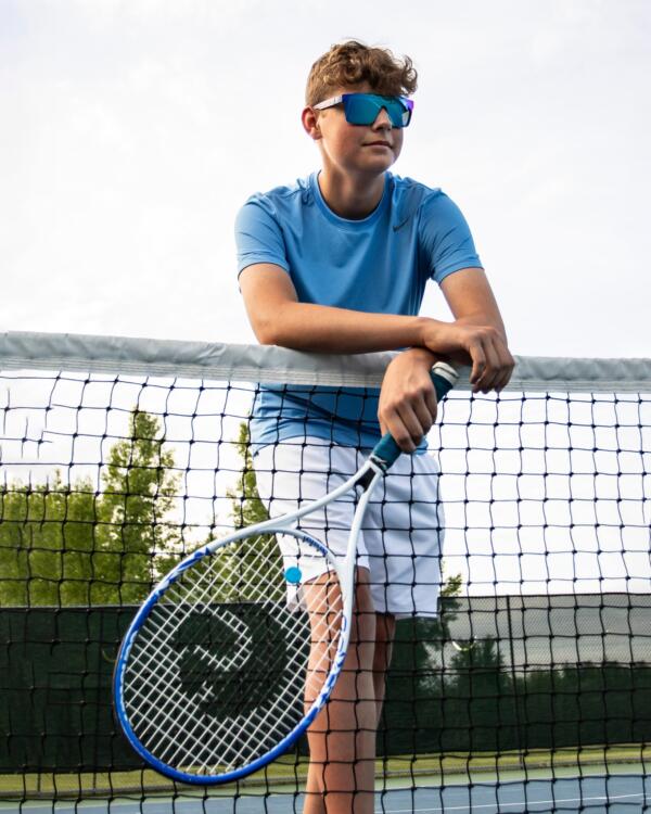 Boy leaning against a tennis net