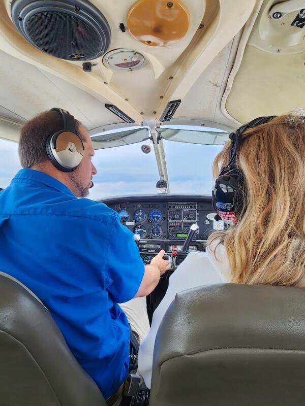 Pilot and woman in the front seat of a plane with control panels in front of them.
