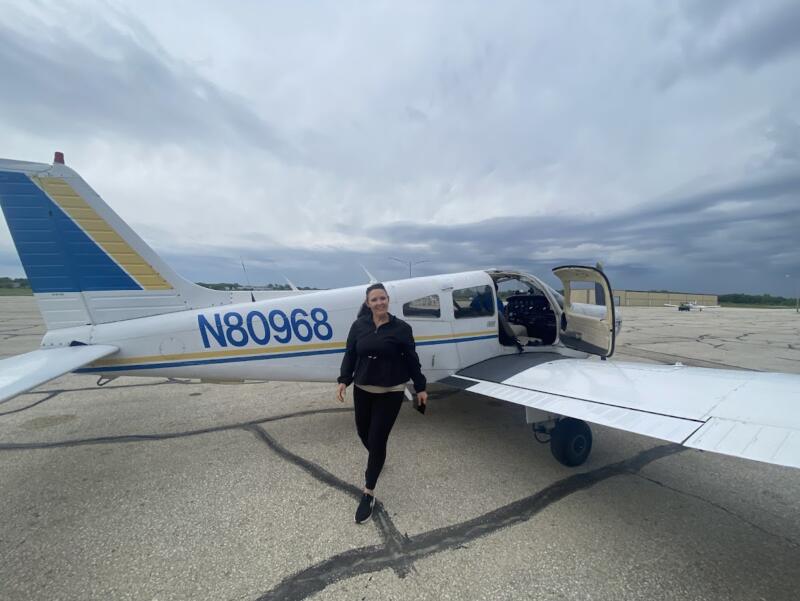 Woman standing outside of small plane at the Watertown Municipal Airport in Watertown Wi