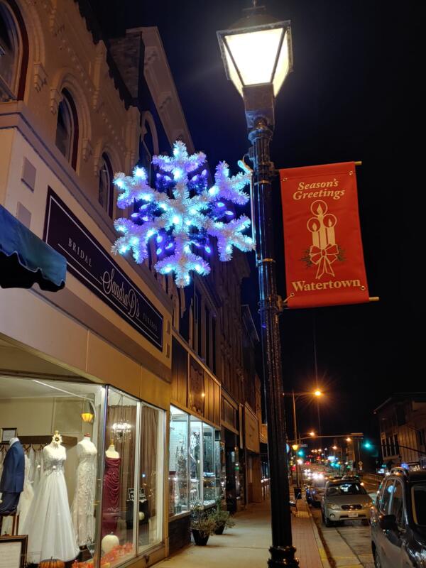 LED snowflake and holiday banner on a lammpost next to a bridal store