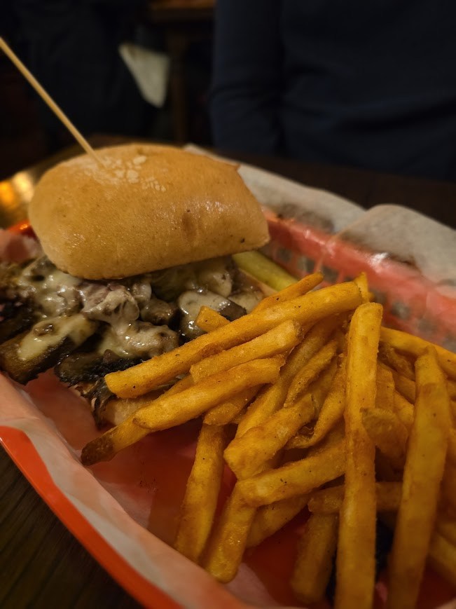 steak sandwich in a basket with fries
